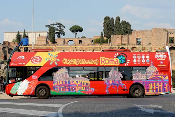 Bus turístico recorriendo Roma,junto al Foro Romano